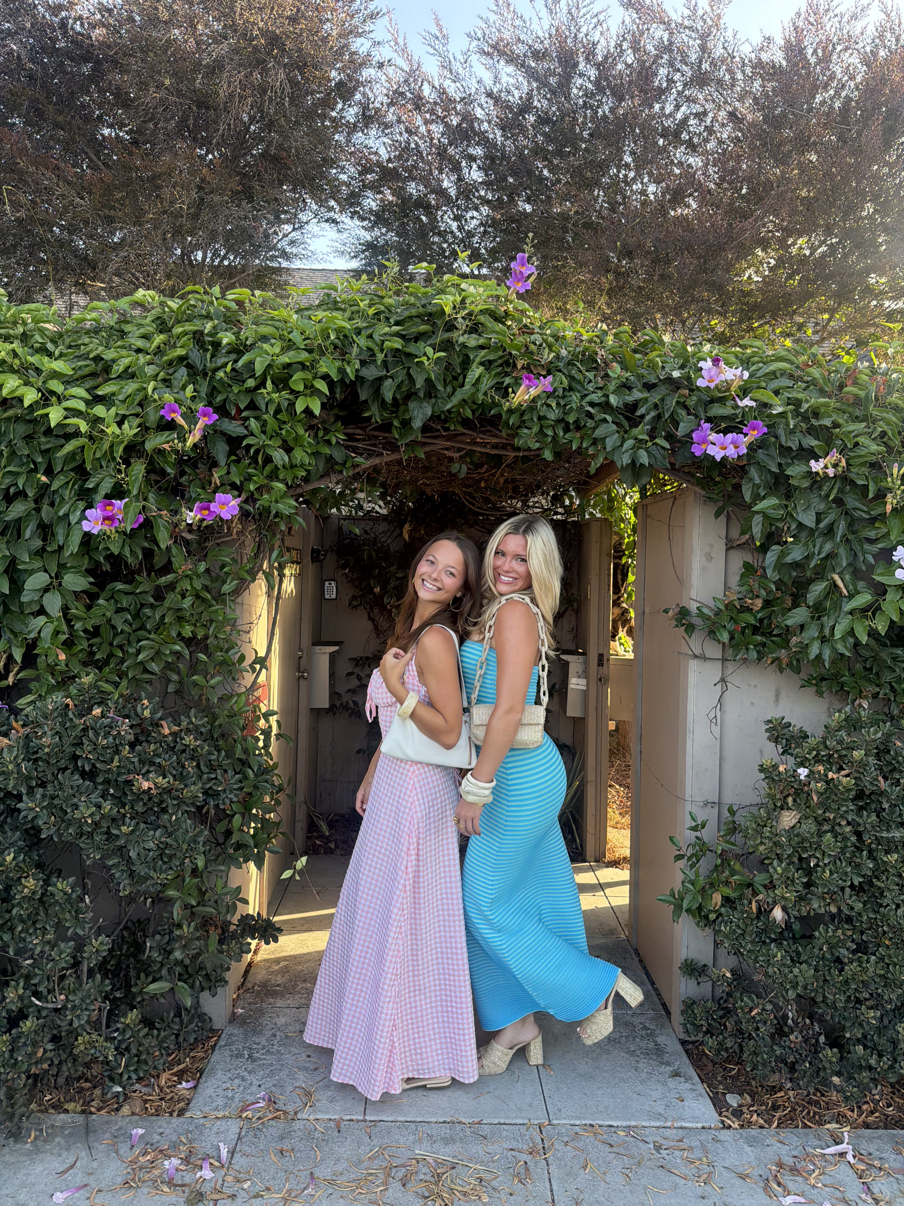 Taylor and Shelby smiling together under a flowering garden archway