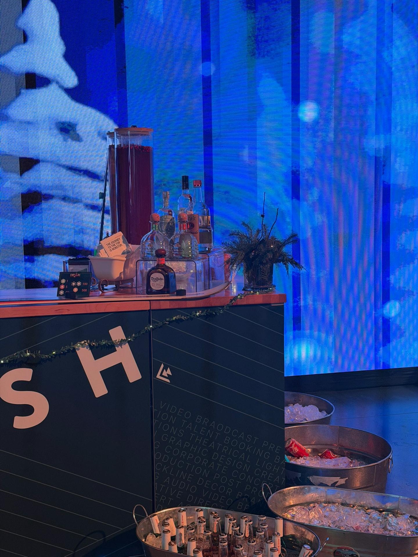 Bar setup with punch dispenser and spirits against a blue winter LED wall