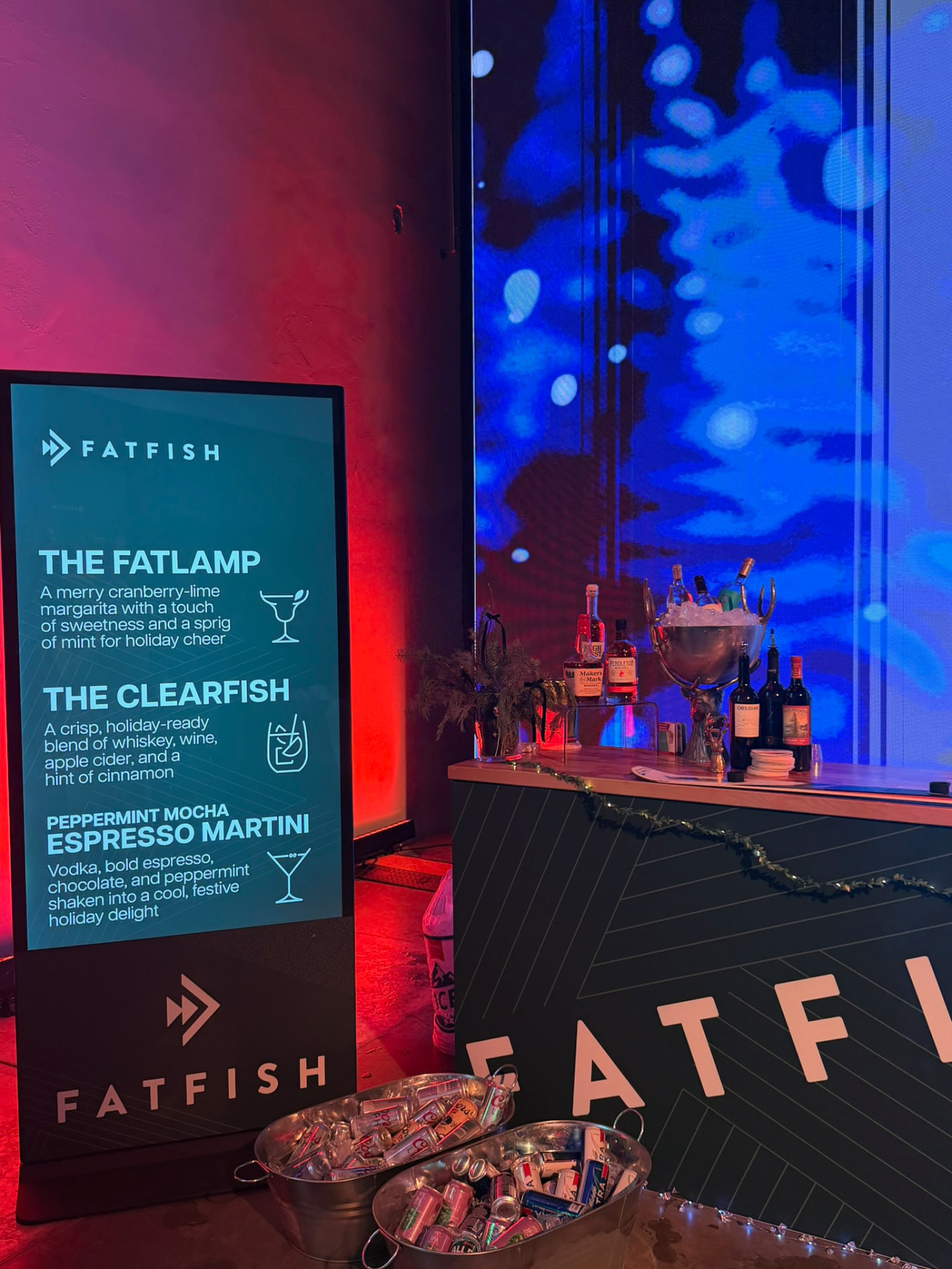 Illuminated cocktail menu beside a holiday bar in red and blue light