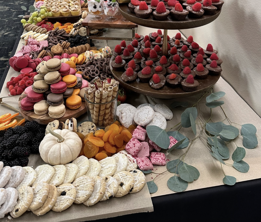 Long dessert table with macarons, chocolate tarts and raspberries