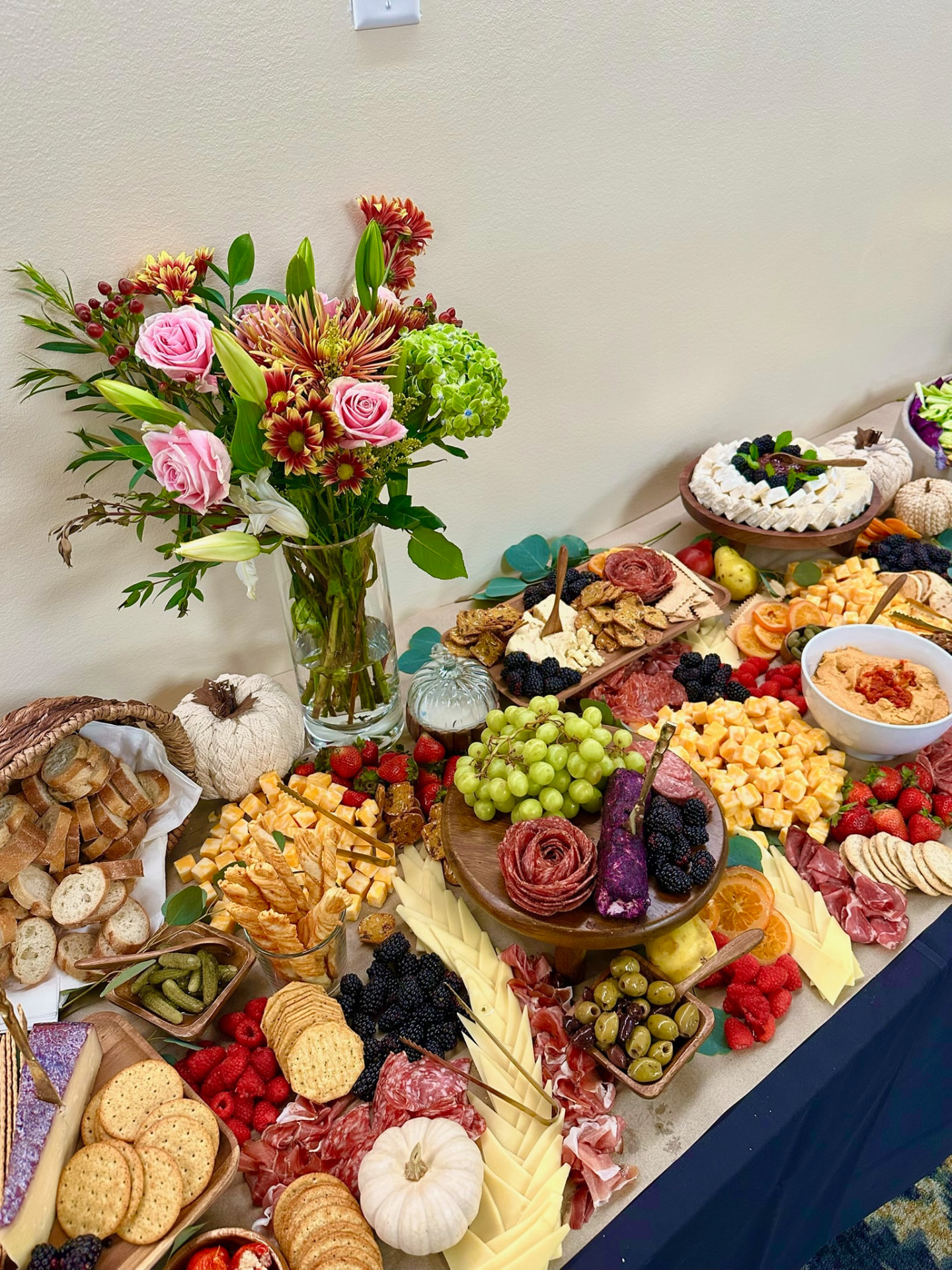 Autumn grazing table with cheeses, charcuterie roses, bread and florals